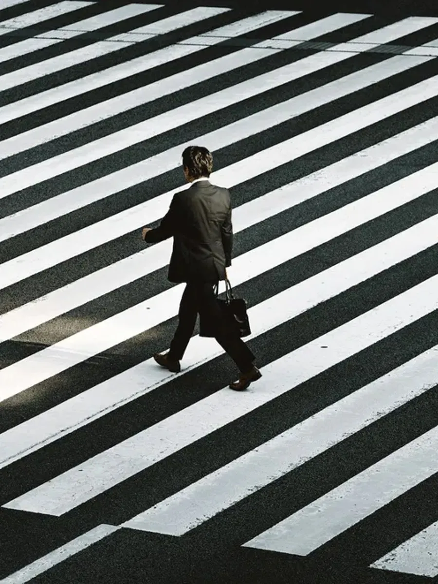 Thomas Uder Vermögensgestaltung – Geschäftsmann mit Aktentasche überquert einen Zebrastreifen